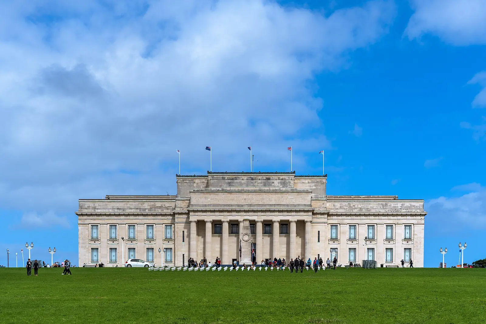 Die Vorderseite des Auckland War Memorial Museum, ein säulengeschmücktes neoklassizistisches Gebäude aus hellem Stein, gesehen über den davorliegenden Rasen